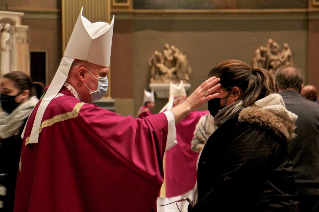 202 02 17-e lee-philadelphia basilica of saints peter and paul-ash wednesday services cross A priest uses his thumb to draw a cross of ashes on the forehead of a parishioner during an Ash Wednesday Mass at the Basilica of Saints Peter and Paul in Philadelphia. (Emma Lee/WHYY)