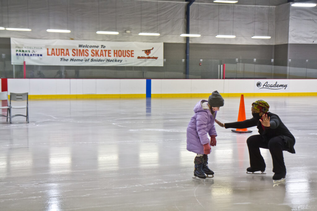 2021 02 05 k paynter city skating rinks open-7 Skate instructor Sultana Afifiah helps a new skater at Laura Sims Skatehouse in Philadelphia. The city’s rinks are reopening with COVID restrictions in February. (Kimberly Paynter/WHYY
