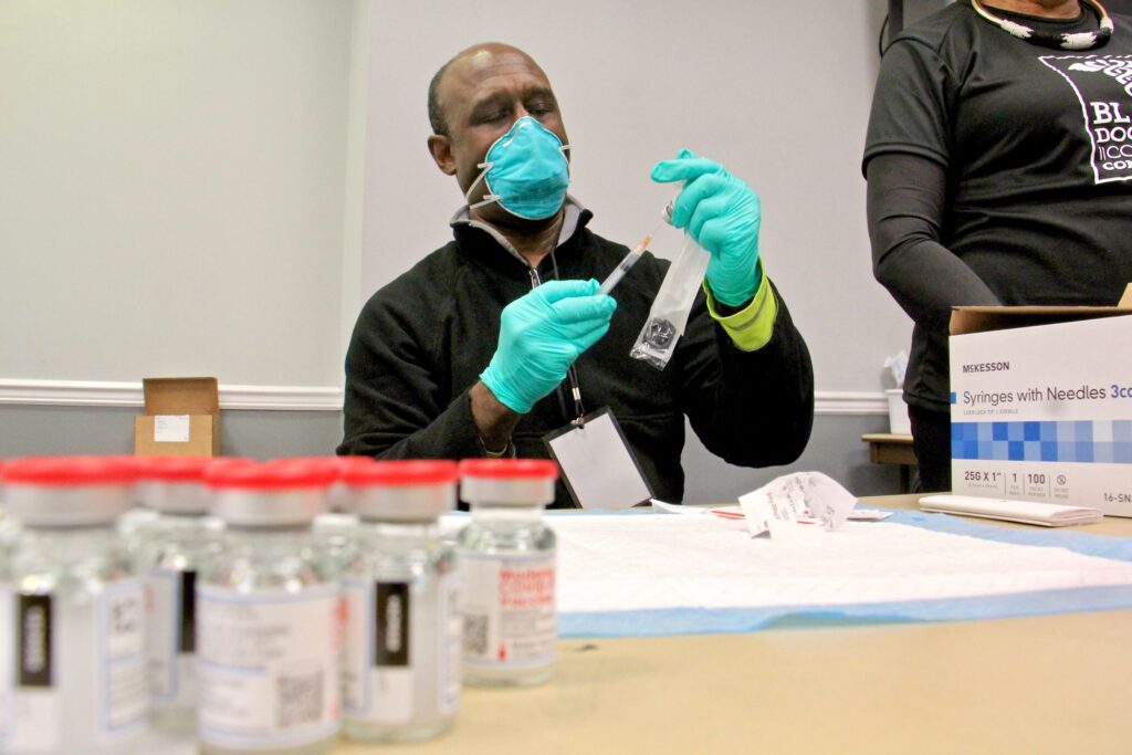 2021 02 19-e lee-christophe debrady-philadelphia temple university liacouras center-black doctors covid 19 consortium vaccination clinic vials Dr. Christophe DeBrady of the Black Doctors COVID-19 Consortium prepares doses of vaccine for the hundreds who turned out for a mass vaccine clinic at the Liacouras Center at Temple University. (Emma Lee/WHYY)