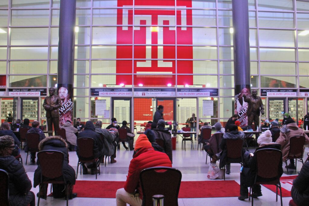 Philadelphians wait in the lobby of the Liacouras Center at Temple University to receive the Moderna COVID-19 vaccine.