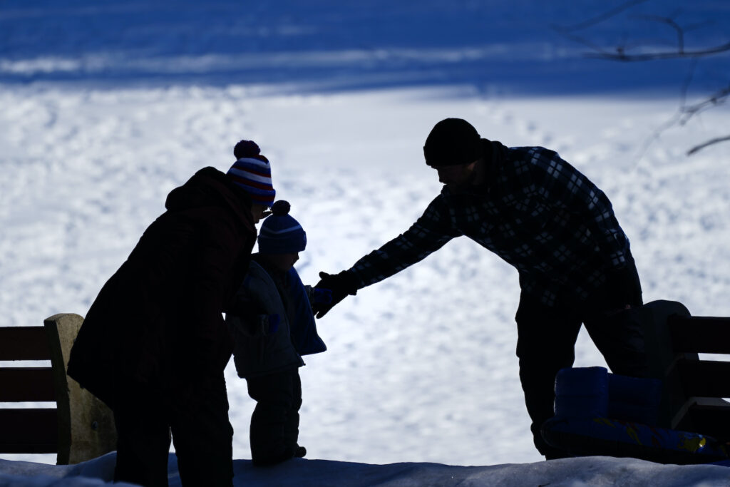 Pennsylvania Daily Life A couple helps a child on a snow covered embankment at Lorimer Park in Huntingdon Valley, Pa., Friday, Feb. 5, 2021. (AP Photo/Matt Rourke)