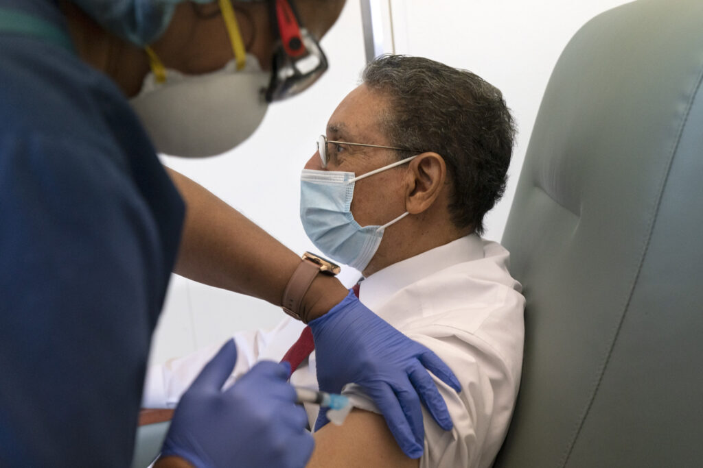 Michelle Martin, Wallace Charles Smith In this Wednesday, Feb. 10, 2021, photo Wallace Charles Smith, 72, who is a pastor at Shiloh Baptist Church, receives his first COVID-19 vaccination by nurse Michelle Martin, at United Medical Center in southeast Washington. (AP Photo/Jacquelyn Martin)