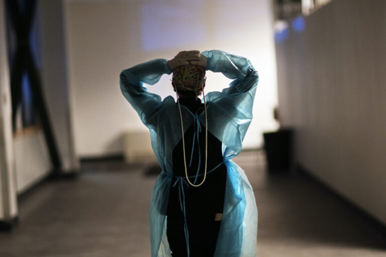 A nurse walks down a hallway with her arms in the air, clasping the back of her head