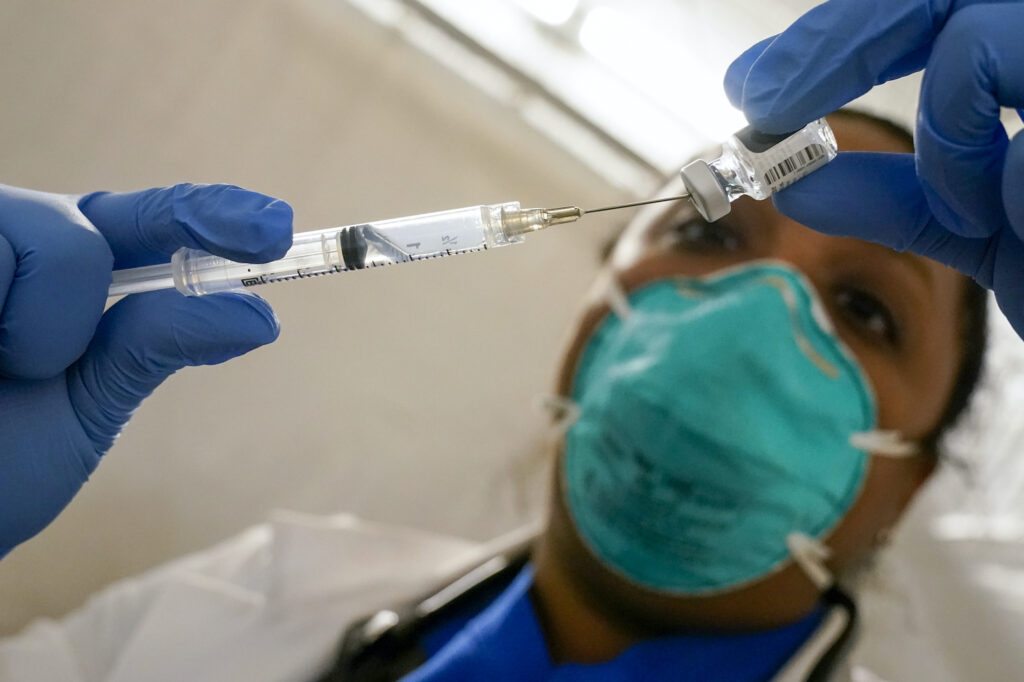 Virus Outbreak US Surge A doctor extracts COVID-19 vaccine out of a vial