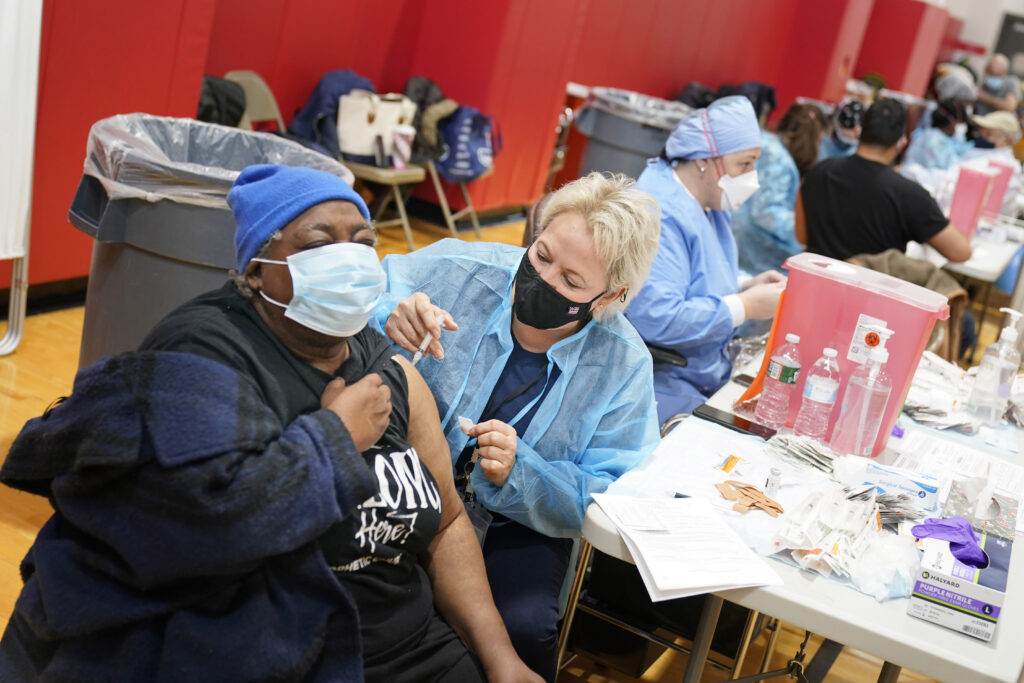 Virus Outbreak US Surge Mary Jenkins, left, receives the COVID-19 vaccine in Paterson