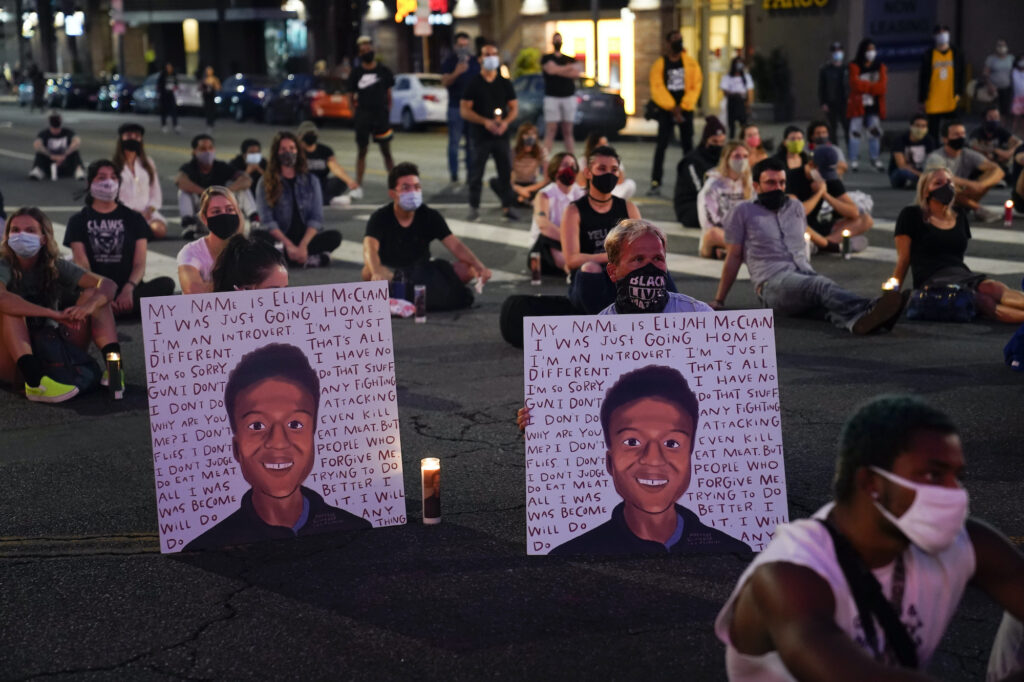 Racial Injustice Elijah McClain In this Aug. 24, 2020, file photo, two people hold posters showing images depicting Elijah McClain during a candlelight vigil for McClain outside the Laugh Factory in Los Angeles. (AP Photo/Jae C. Hong, File)