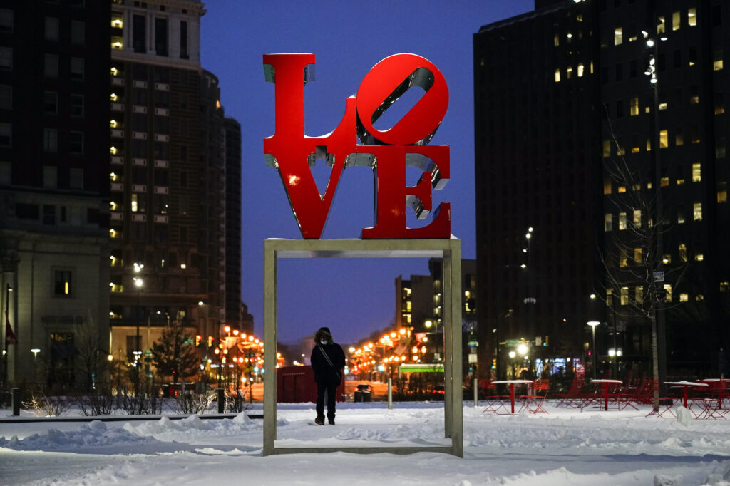 APTOPIX Winter Weather Pennsylvania A person wearing a face mask as a precaution against the coronavirus walks during a winter storm near the Robert Indiana sculpture