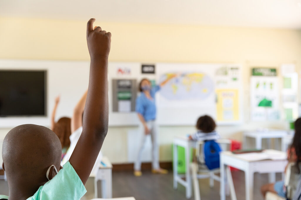 Caucasian female teacher wearing face mask at school, teaching c Classroom during coronavirus pandemic
