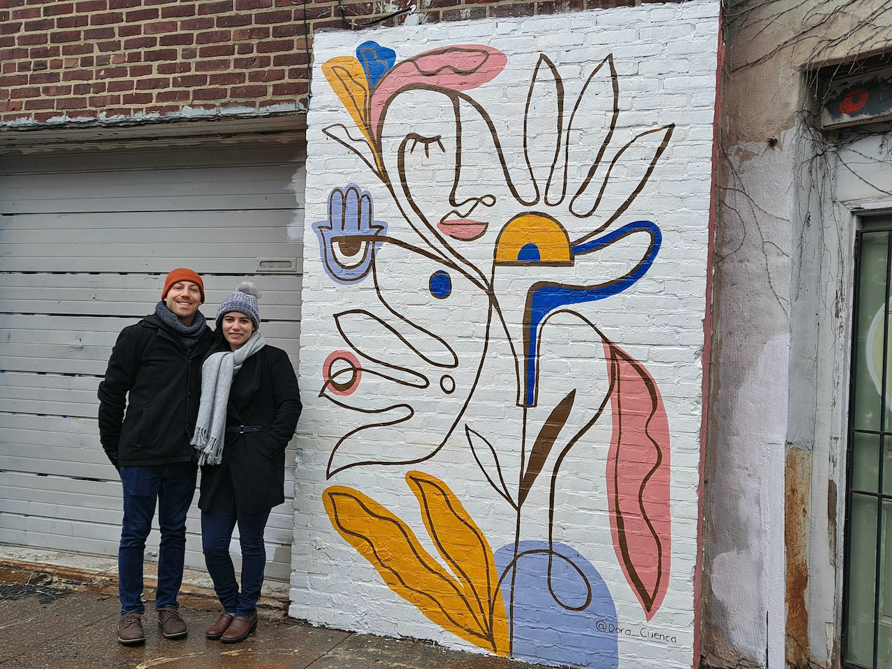 Danielle Brief and Jonah Adams stand next to a mural in South Philly