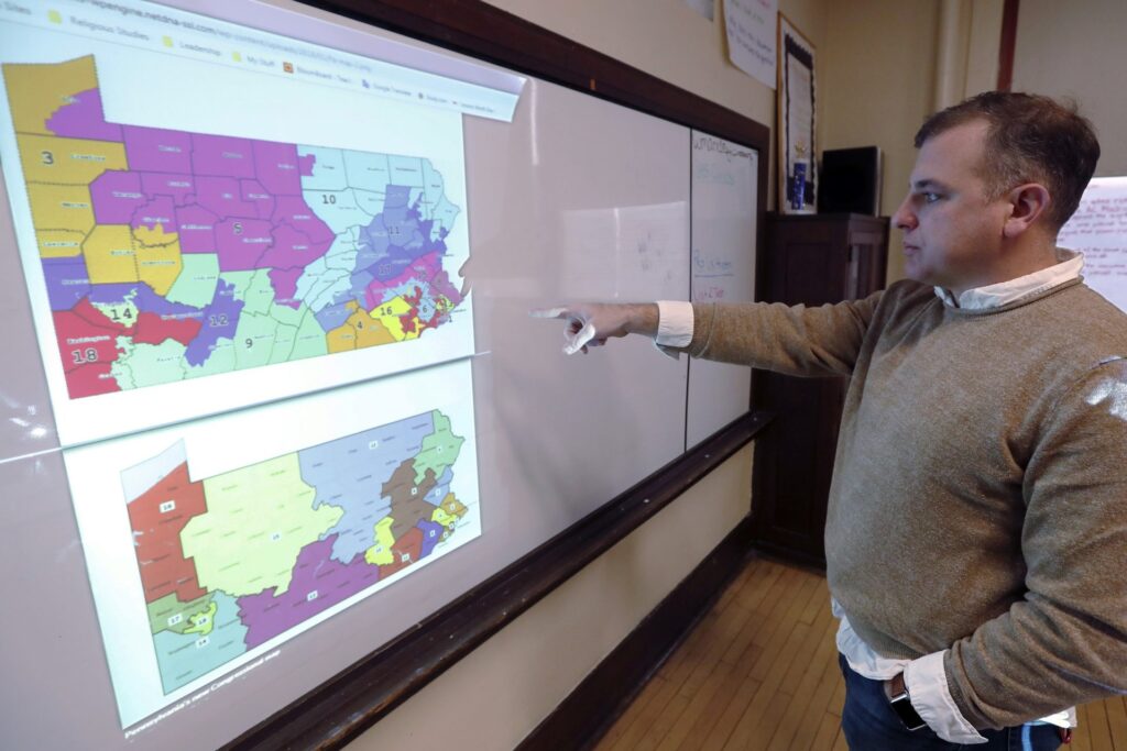 redistricting_file-1920×1280 William Marx, points to projected images of the old congressional districts of Pennsylvania on top, and the new re-drawn districts on the bottom, while standing in the classroom where he teaches civics in Pittsburgh on Friday, Nov. 16, 2018. (Keith Srakocic/AP Photo)