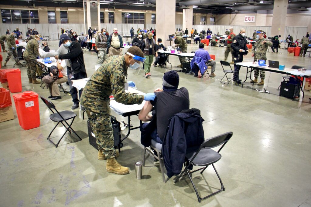 2021 03 02-e lee-philadelphia pennsylvania convention center-fema mass vaccine center shot wide A National Guard member vaccinates someone against COVID-19 at the Pennsylvania Convention Center