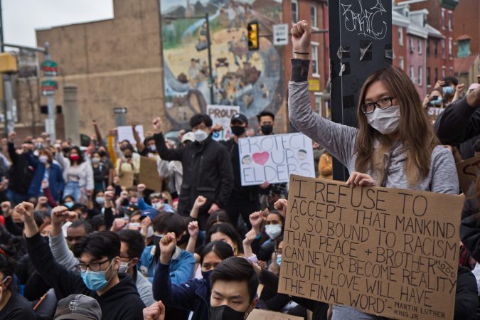 Participants at a solidarity rally at 10th and Vine streets raised fists against white supremacy and violence against their communities on March 25, 2021. (Kimberly Paynter/WHYY)