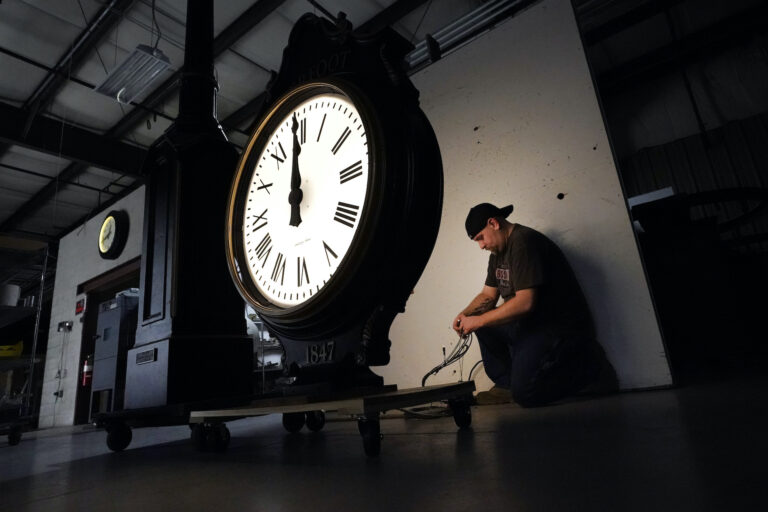 Electric Time technician Dan LaMoore lights up a two-dial Howard Post Clock, Tuesday, March 9, 2021, in Medfield, Mass. Daylight saving time begins at 2 a.m. local time Sunday, March 14, 2021, when clocks are set ahead one hour. (AP Photo/Elise Amendola)