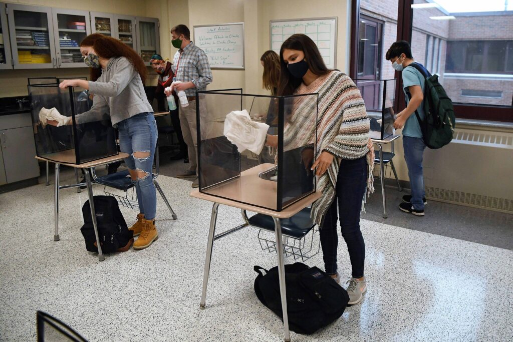 Virus Outbreak In this March 18, 2021, file photo, students in teacher Christopher Duggan's science class clean their work areas at the end of class at Windsor Locks High School in Windsor Locks, Conn. (AP Photo/Jessica Hill)