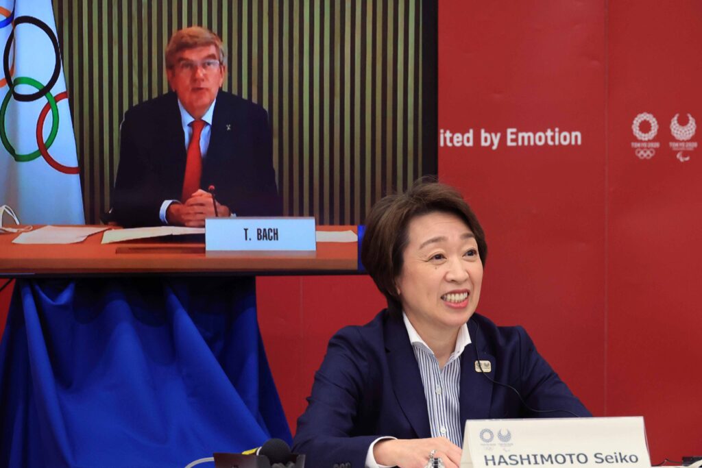 Japan Tokyo Olympics International Olympic Committee (IOC) President Thomas Bach, on a screen, delivers an opening speech while Tokyo 2020 Organizing Committee President Seiko Hashimoto listens at a five-party meeting of Tokyo 2020 Olympic and Paralympic Games with International Paralympic Committee (IPC) President Andrew Parsons, Tokyo Gov. Yuriko Koike and Japanese Olympic Minister Tamayo Marukawa in Tokyo Saturday, March 20, 2021. (Yoshikazu Tsuno/Pool Photo via AP)