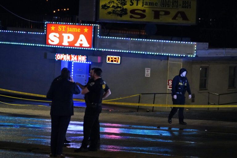 Officials stand in front of a massage parlor after a shooting