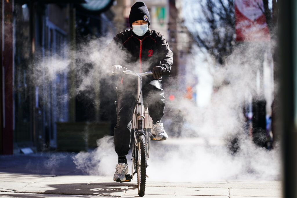 A person wearing a face mask as a precaution against the coronavirus rides a bicycle in Philadelphia