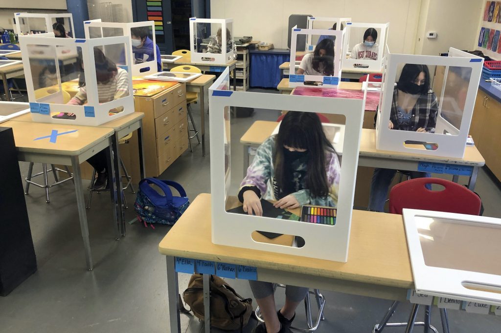 Virus Outbreak Schools Physically distanced, and with protective partitions, students work on an art project during class