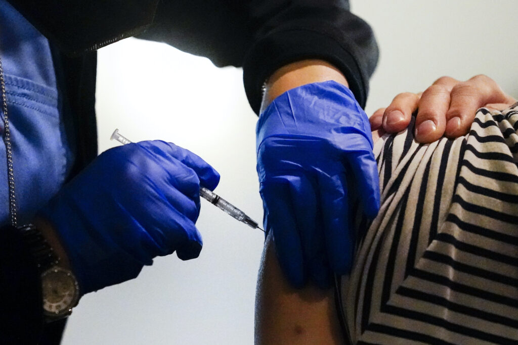 A health worker administers a dose of a Pfizer COVID-19 vaccine