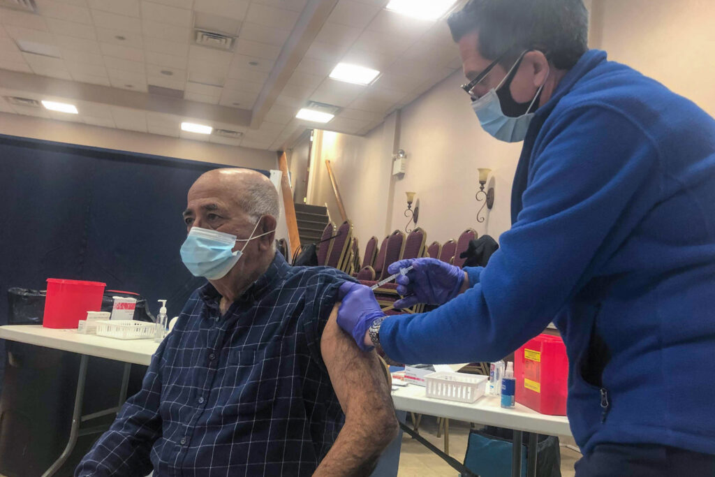 Image-from-iOS-(68) Joseph Dymowski, co-owner of Centennial Pharmacy, vaccinates Costa Monsour, a parishioner at St. Maron Maronite Catholic Church. (Nina Feldman / WHYY)