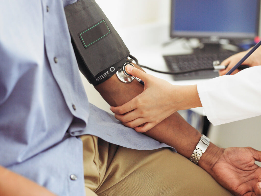 200489720-001 A white health care worker takes the blood pressure of a Black patient