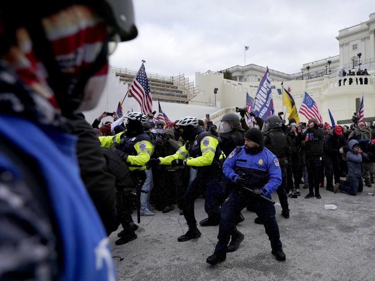 Police officers try to push back pro-Trump insurrectionists trying to break through a police barrier
