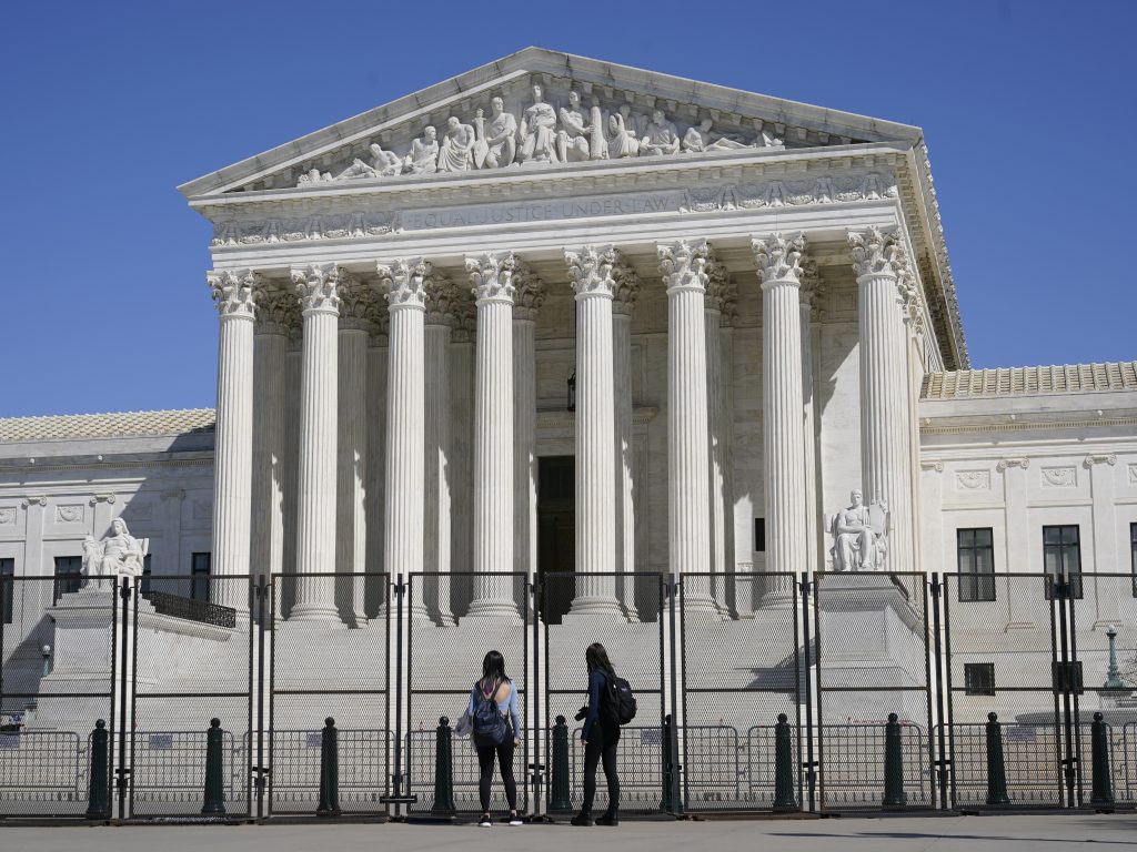 The U.S. Supreme Court heard arguments in a case testing whether police may enter a person’s home and seize guns without a warrant in order to safeguard the homeowner from potential harm. People view the Supreme Court building from behind security fencing on Capitol Hill