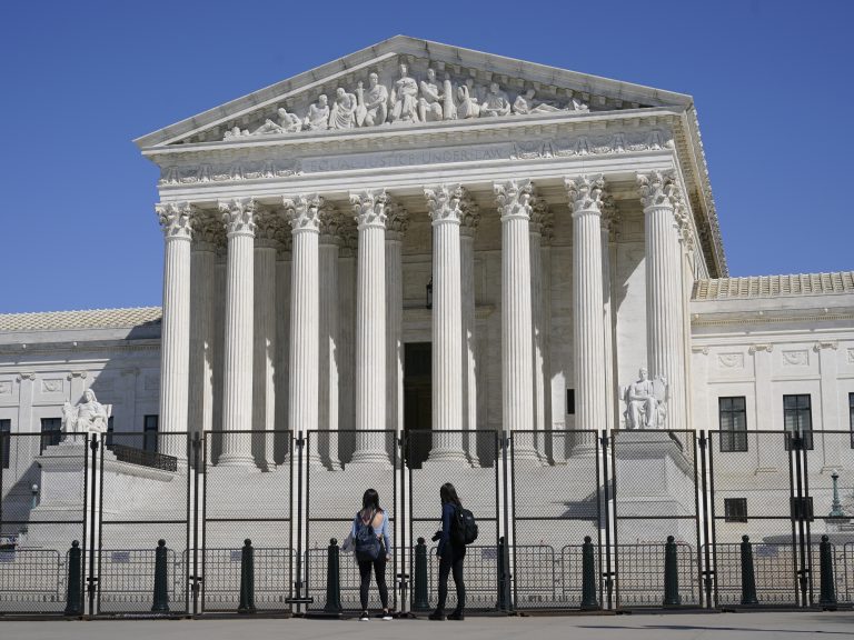 People view the Supreme Court building from behind security fencing on Capitol Hill