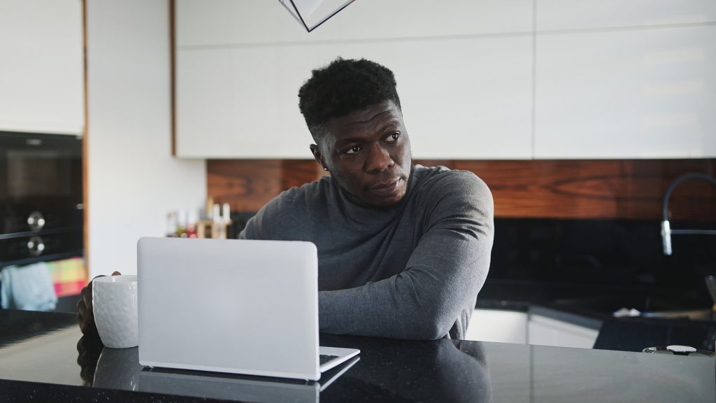 Young African American Black Man Working On Laptop In His Appart A young Black man working on laptop in his apartment