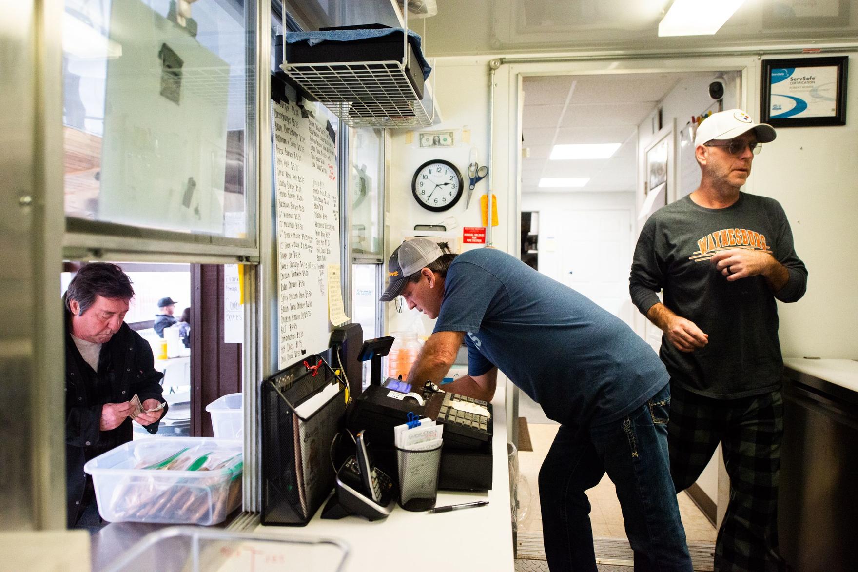 Bob Morris, center, owner of Burgers & More, takes a customer order while working with his brother, Scott Morris, right, at the family burger business in Waynesburg