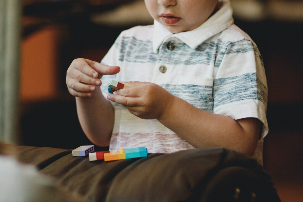 caleb-woods-ecRuhwPIW7c-unsplash Young child plays with Legos.