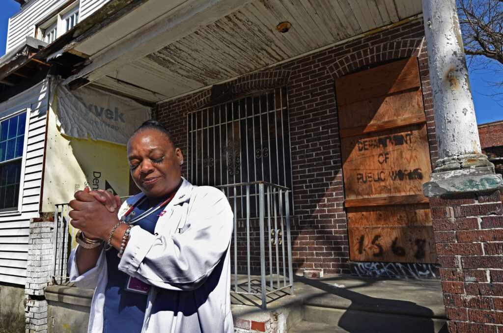 Carlita Smith holds her hands together in prayer in front of a Camden home