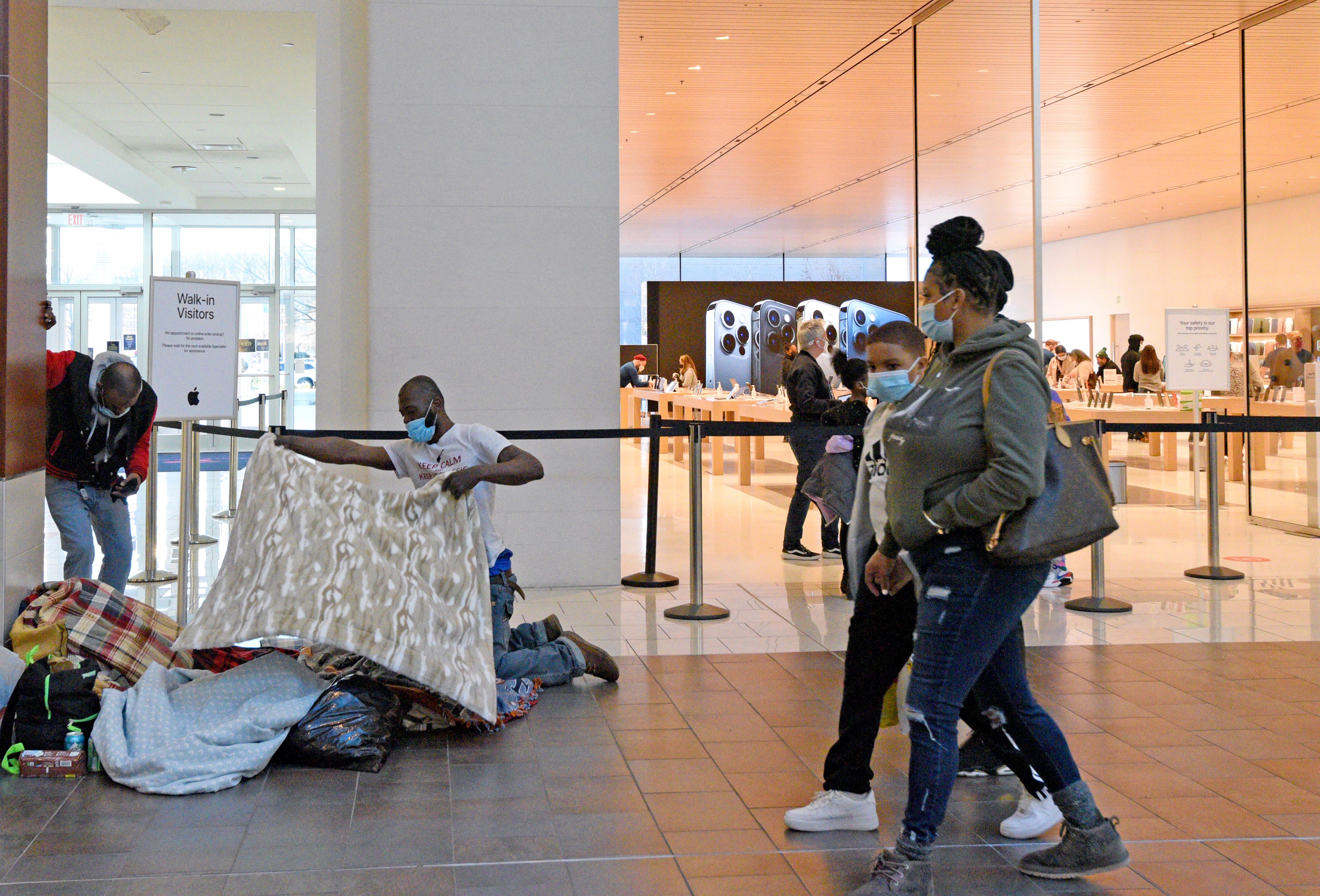 Unhoused individuals spread blankets on the floor of the Cherry Hill Mall
