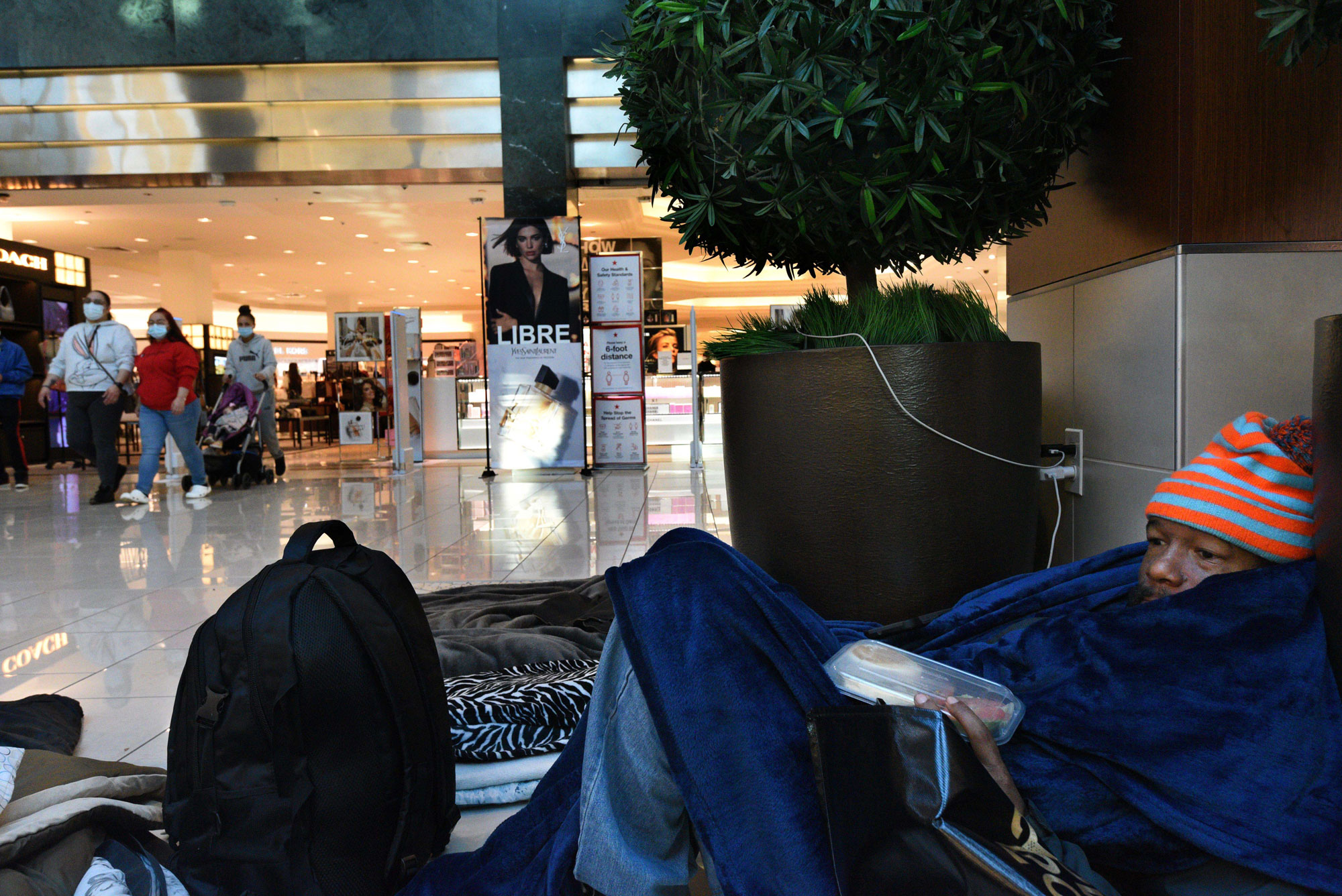 An unhoused individual reclines on the floor of the Cherry Hill Mall