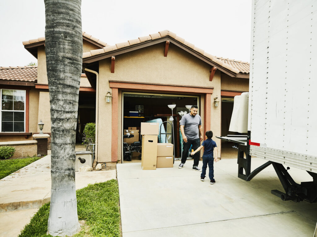 Young son helping father move items from moving truck into new house Young son helping father move items from moving truck into new house