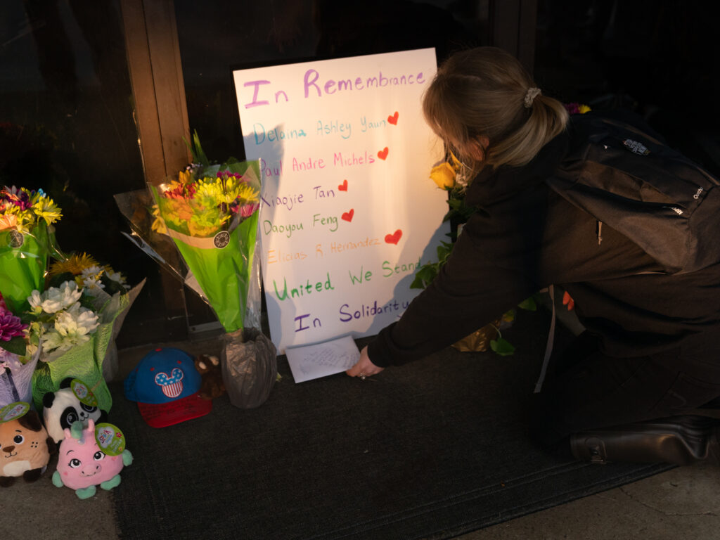 Shelby Swan places a sign outside Youngs Asian Massage, where four people were shot and killed this week in Acworth, Ga. Another four people were fatally shot at two massage businesses in Atlanta, but authorities have not released their names. Flowers and signs adorn Gold Spa during a demonstration protesting violence against women and Asians following Tuesday night's shooting in the Atlanta area which killed eight. (Megan Varner/Getty Images)