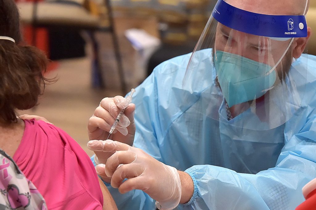 A federal program administered nearly 8 million COVID vaccine doses in nursing homes, reaching the majority of residents. But many staff members chose not to get the shot. A health worker administers a COVID-19 vaccine
