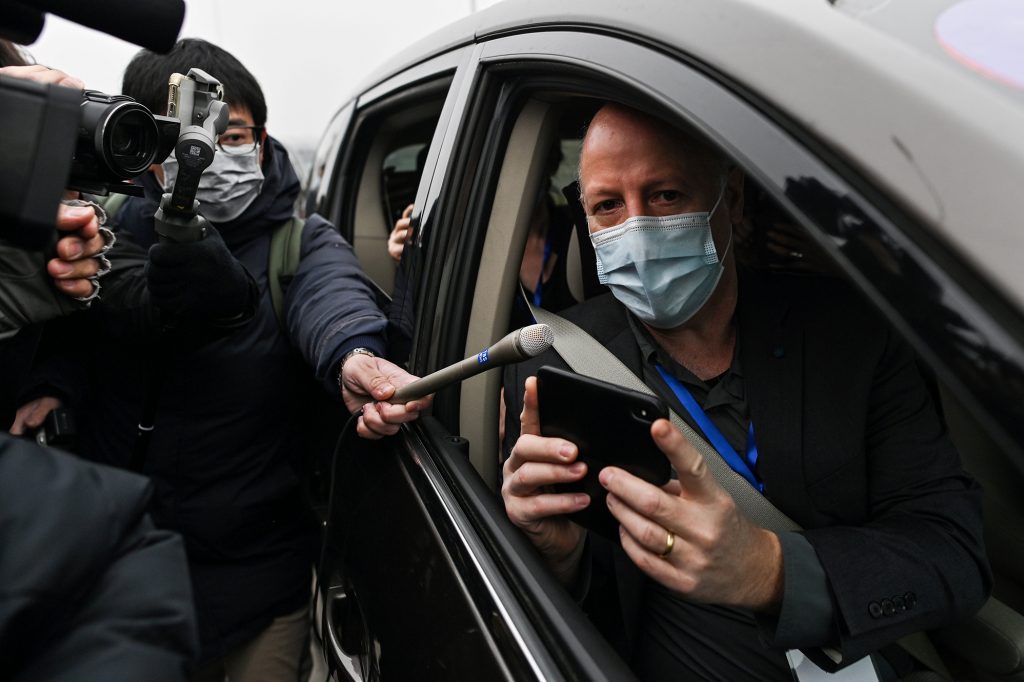 World Health Organization investigative team member Peter Daszak (shown here during a trip to China in February) tells NPR that the group’s report calls for additional research on farms that breed exotic animals in southern China. Peter Daszak holds up a phone from the passenger seat of a car while wearing a mask