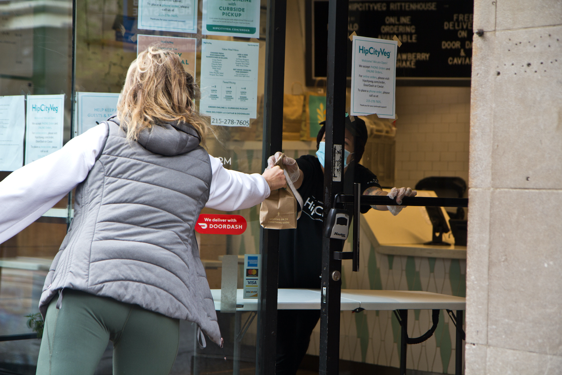 An employee hands off a to-go order through the door of HipCityVeg