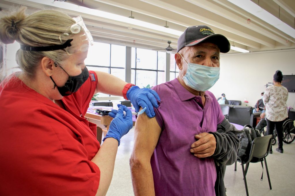 2021 04 09-e lee-gail bagnato eduardo delgadocamden nj westfield towers-county vaccine clinic Eduardo Delgado gets his COVID-19 vaccination from Gail Bagnato