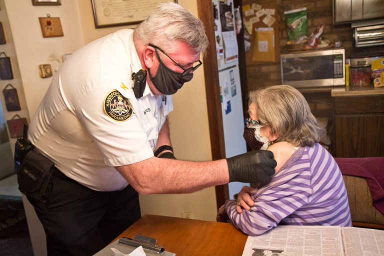 Paramedic Jim McCanns prepares to administer a first dose of the Moderna COVID-19 vaccine to Lucille Breslin at her home in Upper Darby on April 6, 2021. (Kimberly Paynter/WHYY)