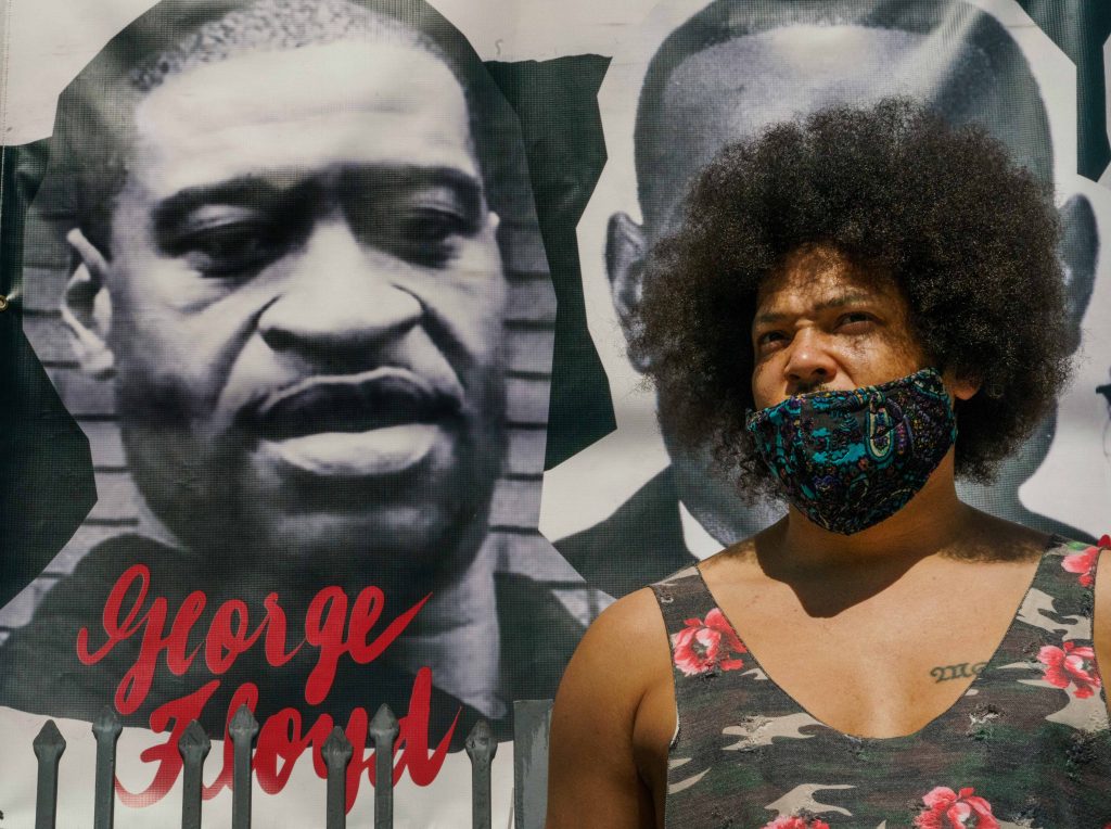 Actor Steven Thompson poses for a picture next to a poster of George Floyd in Los Angeles Friday, April 2, 2021. (AP Photo/Damian Dovarganes)