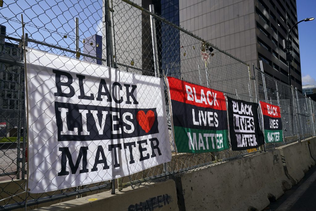 Signs and flags line the fence at the Hennepin County Government Center