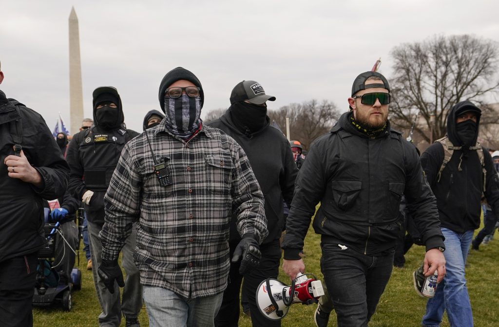Proud Boy members Joseph Biggs (left) and Ethan Nordean, carrying a megaphone, walk toward the U.S. Capitol on Jan. 6. A federal judge ordered them detained pending trial given the conspiracy charges against them. Proud Boy members Joseph Biggs (left) and Ethan Nordean, carrying a megaphone, walk toward the U.S. Capitol on Jan. 6. A federal judge ordered them detained pending trial given the conspiracy charges against them. (Carolyn Kaster/AP)
