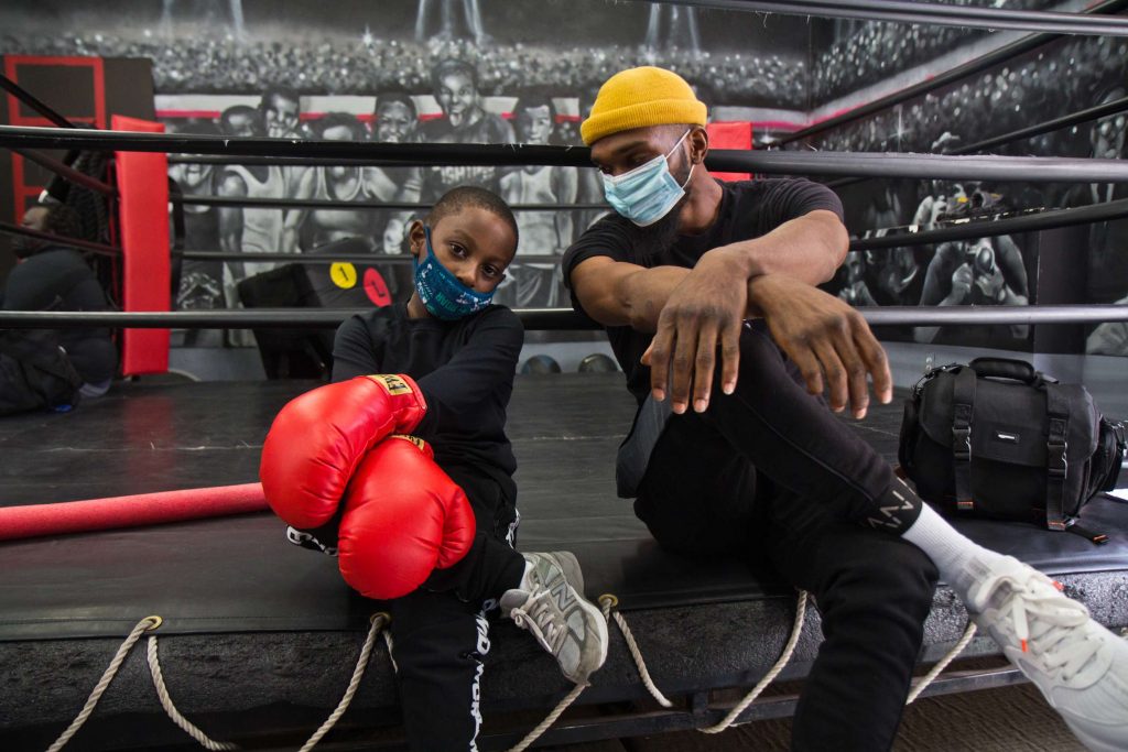8 year-old Lewis King hangs with Maleek Jackson at his boxing gym in Northern Liberties. (Kimberly Paynter/WHYY)