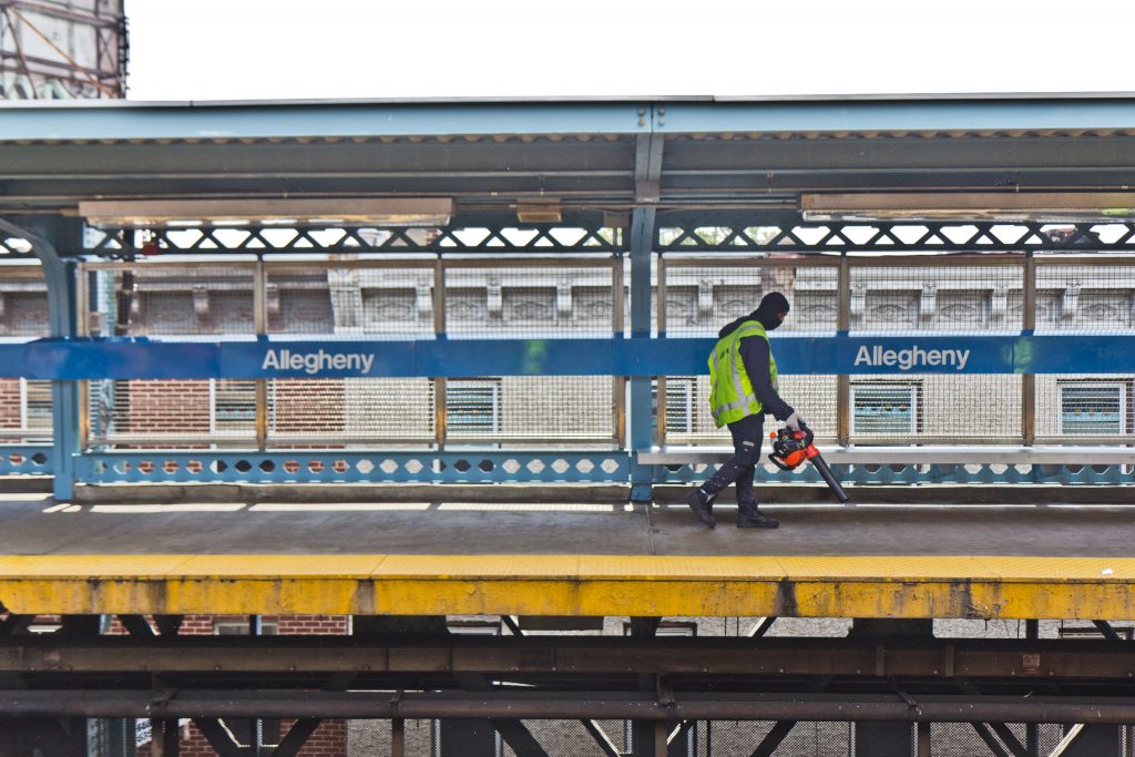 2021-05-6-k-paynter-kensington-ave-walk-with-social-workers-11 File photo: A worker uses a leaf blower to move trash onto the tracks at Allegheny SEPTA station. (Kimberly Paynter/WHYY)