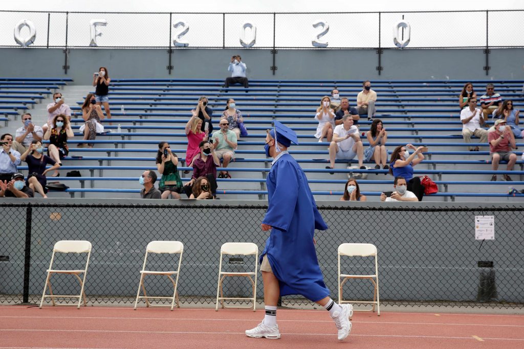 Virus Outbreak New Jersey Students walks past applauding friends and family during a graduation ceremony at Millburn High School in Millburn, N.J., Wednesday, July 8, 2020. (AP Photo/Seth Wenig)