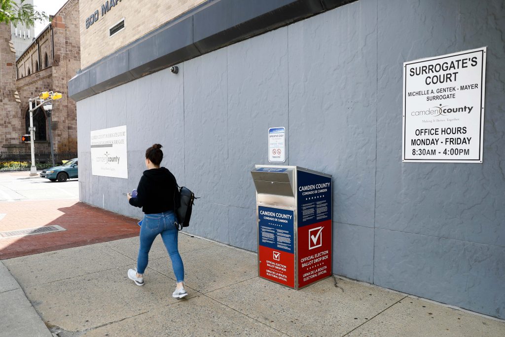 Voting Election Reforms In this July 1, 2020, file photo, a woman walks past a vote-by-mail drop box for the upcoming New Jersey primary election outside the Camden, N.J., Administration Building. (AP Photo/Matt Slocum)