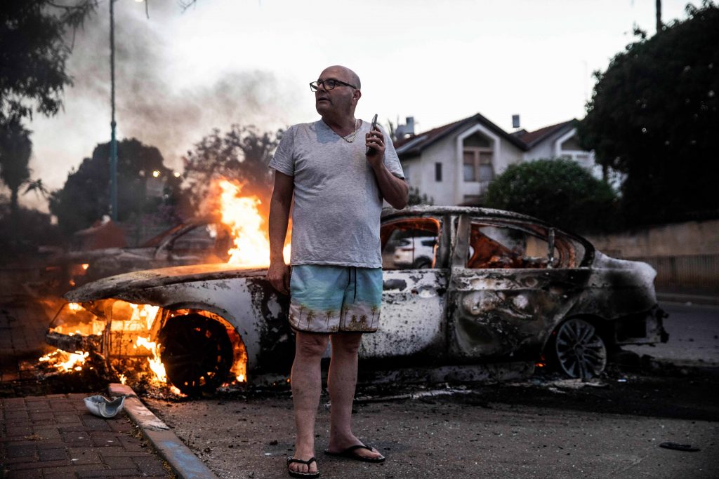 APTOPIX Israel Palestinians Jacob Simona stands by his burning car during clashes with Israeli Arabs and police in the Israeli mixed city of Lod, Israel Tuesday, May 11,2021. (AP Photo/Heidi Levine)