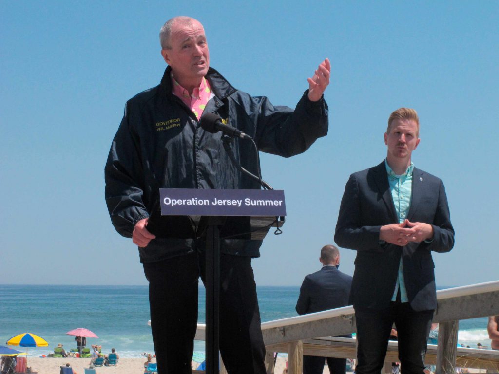 Virus Outbreak-NJ New Jersey Gov. Phil Murphy, left, speaks at a news conference at Island Beach State Park in New Jersey on Wednesday, May 19, 2021, where he announced that the state will give free season-long admission to the park and other state parks to any New Jersey resident who has gotten at least one dose of COVID-19 vaccine by July 4. At right is Shawn LaTourette, the acting environmental protection commissioner. (AP Photo/Wayne Parry)